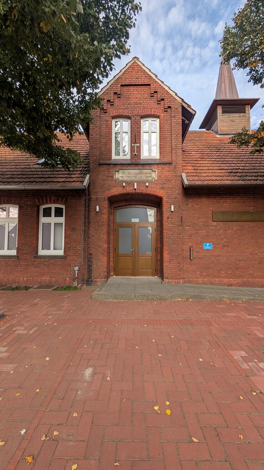 Der Eingang in der Mitte der Front, mit Giebel und Glockenturm