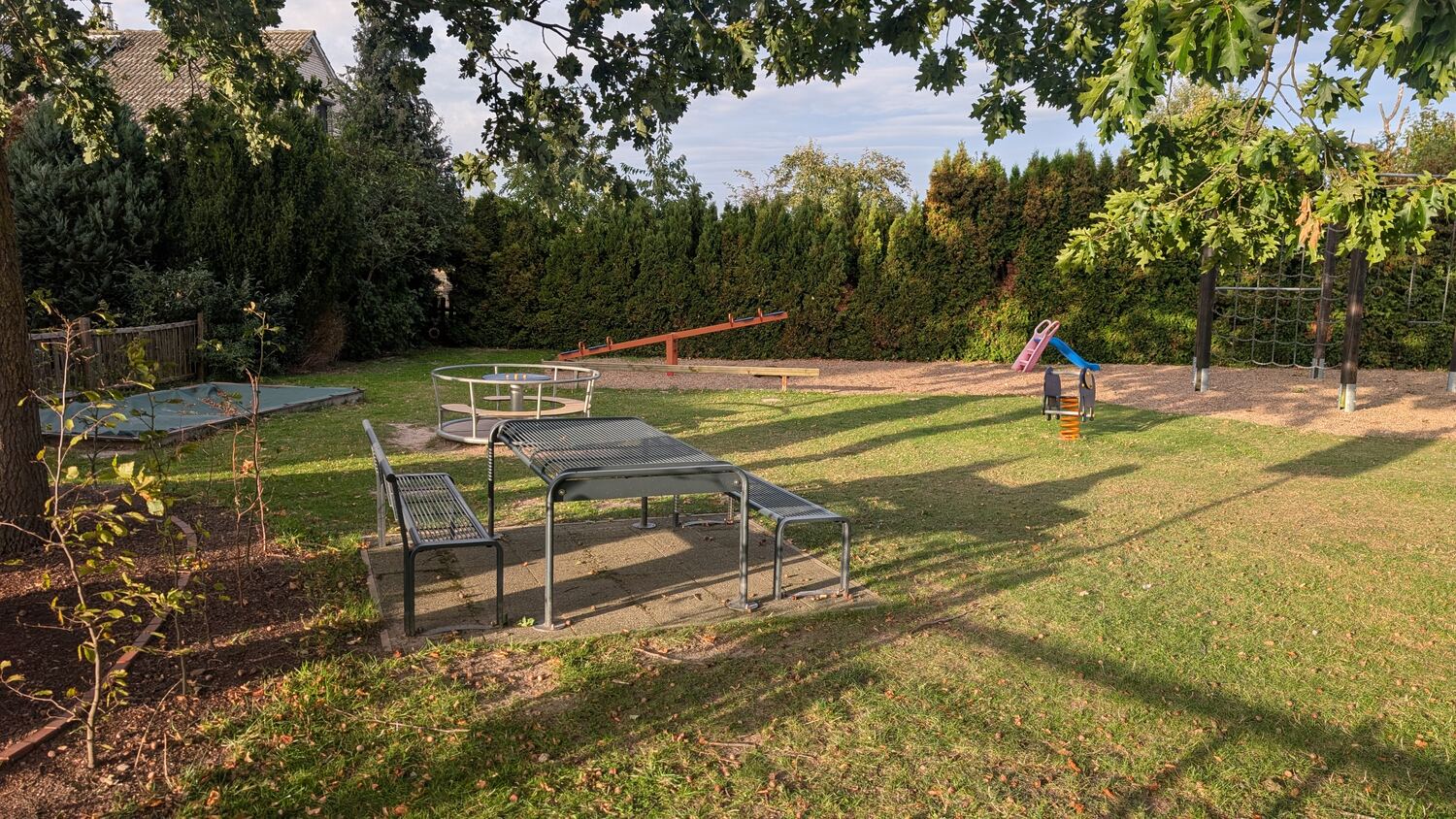 Spielbereich mit Wippe, Karussell, Federwippe und Kletternetz